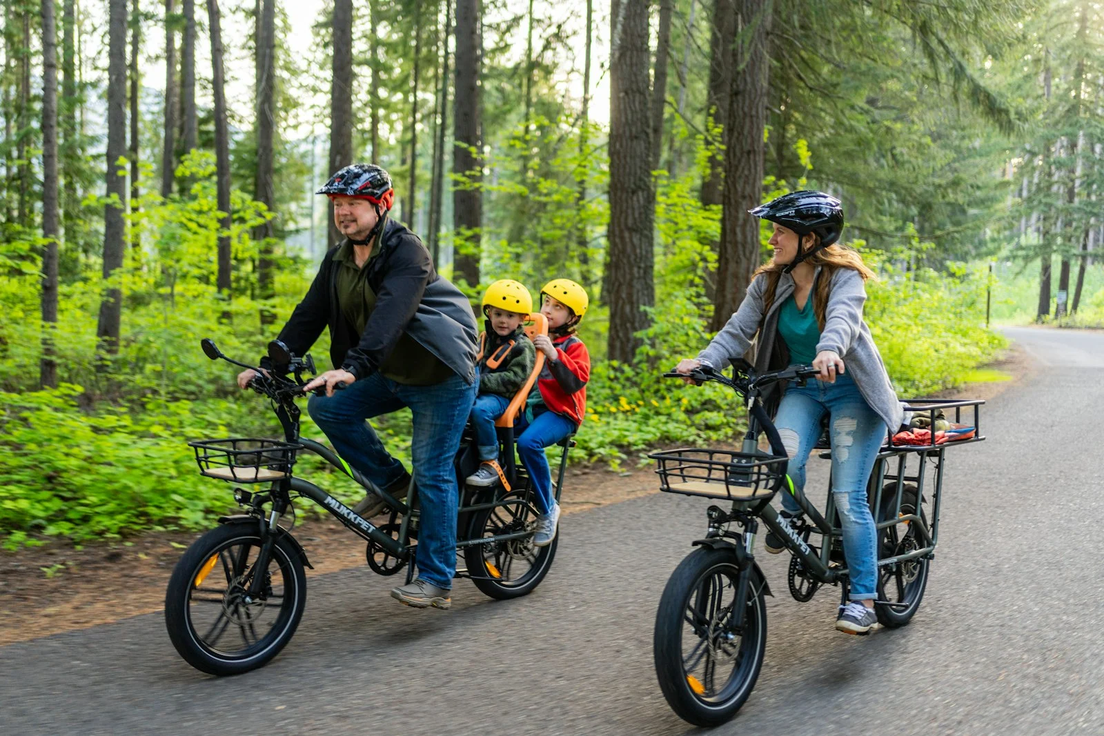 Family riding bikes together on a forest road